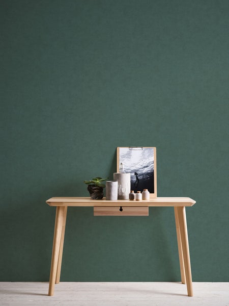 Dekorative Szene mit einem Holztisch, Pflanze, Behältern und einem gerahmten Bild vor einem grünen Hintergrund.