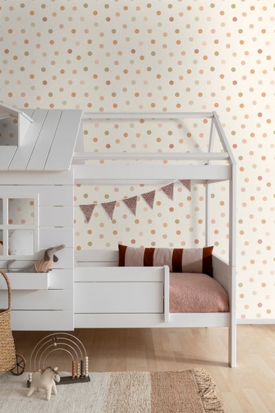 Ein Kinderzimmer mit einem weißen Bett und einer gepunkteten Tapete.