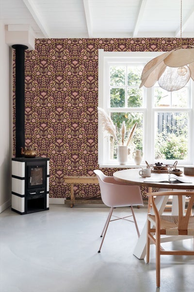 Esszimmer mit gemusterter Tapete, Esstisch, Stühlen und Kaminofen