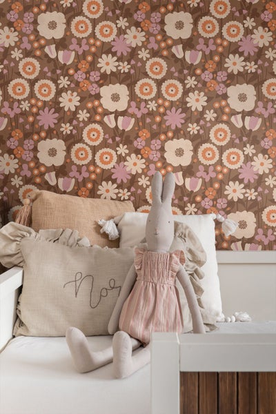 Retro-Tapete mit Blumenmuster in Orange und Rosa in einem Kinderzimmer mit weißem Bett, Kissen und Stofftier-Hase.