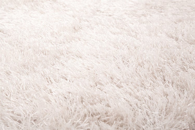 Nahaufnahme eines weichen weißen Hochflor-Teppichs aus Synthetikfasern.