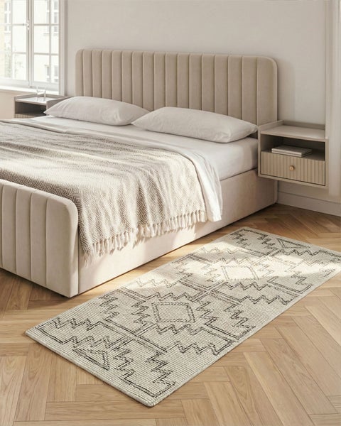 Ein Schlafzimmer mit einem Bett und einem gemusterten Teppich auf dem Holzboden.