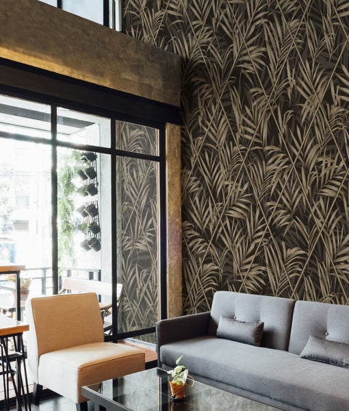 Wohnzimmer mit grauer Couch, Stuhl und gemusterter Tapete mit Palmenmotiven für ein modernes Wohnambiente.