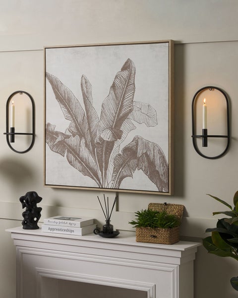 Dekoratives Wohnzimmer mit einem Wandbild, Kerzenhaltern und Zierobjekten auf einem Kaminsims.