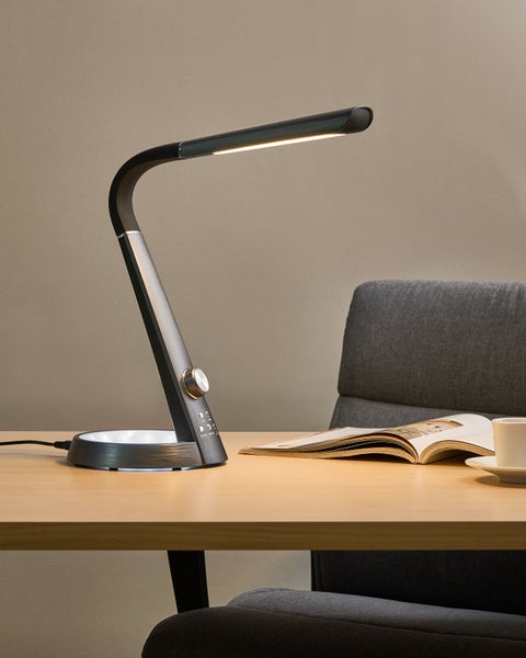 Schreibtischleuchte mit offenem Buch und Kaffeetasse auf einem Schreibtisch