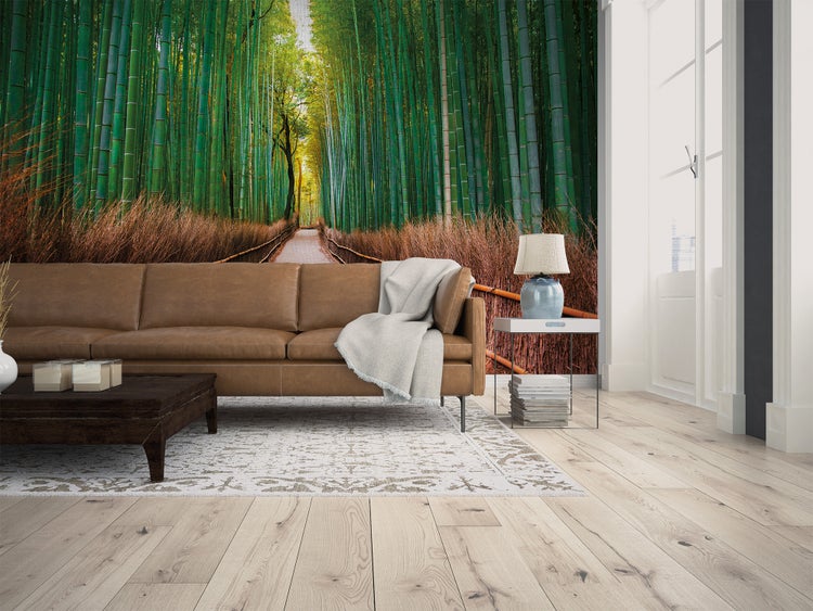 Fototapete mit Bambuswald und Pfad in einem hellen Wohnzimmer mit Ledersofa und Holzboden.