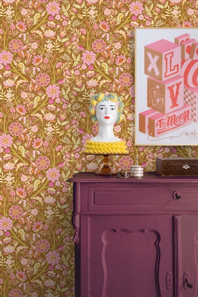 Dekoratives Zimmer mit floraler Tapete, Kommode und Kunstkopf.
