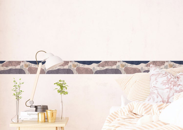 Tapetenbordüre mit botanischem Muster in einem hellen Schlafzimmer mit Bett, Holztisch und weißer Schreibtischlampe.