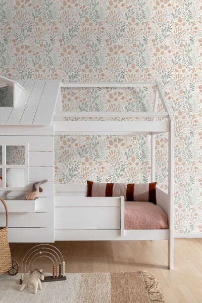 Kinderzimmer mit weißem Hausbett vor einer Wand mit floral gemusterter Tapete, hellem Holzfußboden und Teppich.