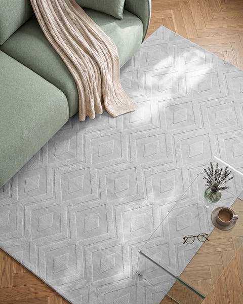 Wohnzimmer mit Sofa, beigem Strickplaid und modernem Teppich mit geometrischem Rautenmuster auf Parkettboden.
