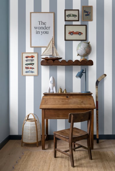 Organisiertes Kinderzimmer mit vertikal gestreifter Tapete, Holzschreibtisch, passendem Stuhl, Wandbildern und Regal im klassischen Stil.