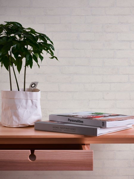 Dekorative Wand mit Backsteintapete, zwei gerahmten Bildern mit den Worten Liebe und Atmen, Topfpflanze und Limetten.