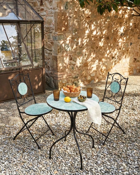 Gartenszene mit Tisch, zwei Stühlen, Speisen und Getränken im Außenbereich