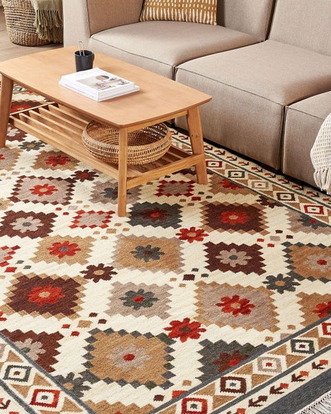 Hochflor Teppich mit rotem Muster, Kissen mit Vogelmotiv und Dekoaccessoires auf einem Tablett