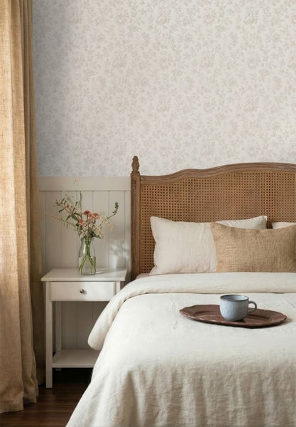 Helles Schlafzimmer mit Blumentapete, Holzbett mit Wiener Geflecht, weißem Nachttisch und Bett mit heller Bettwäsche.