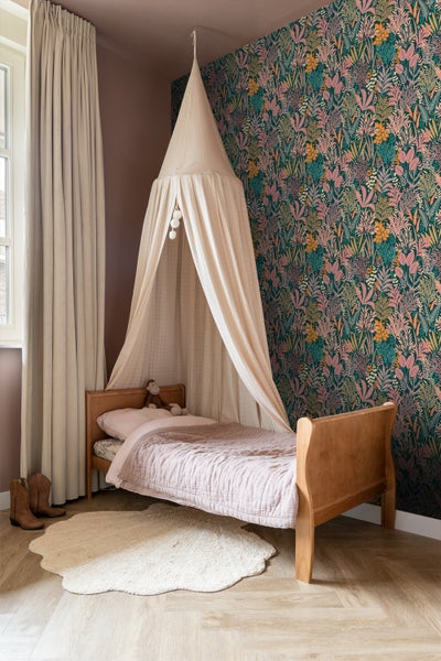 Kinderzimmer mit Himmelbett, floraler Tapete und Teppich
