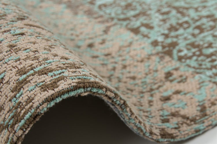 Nahaufnahme eines Teppichs mit Vintage-Muster in Türkis und Braun, strukturierte Oberfläche mit umgeschlagener Kante.