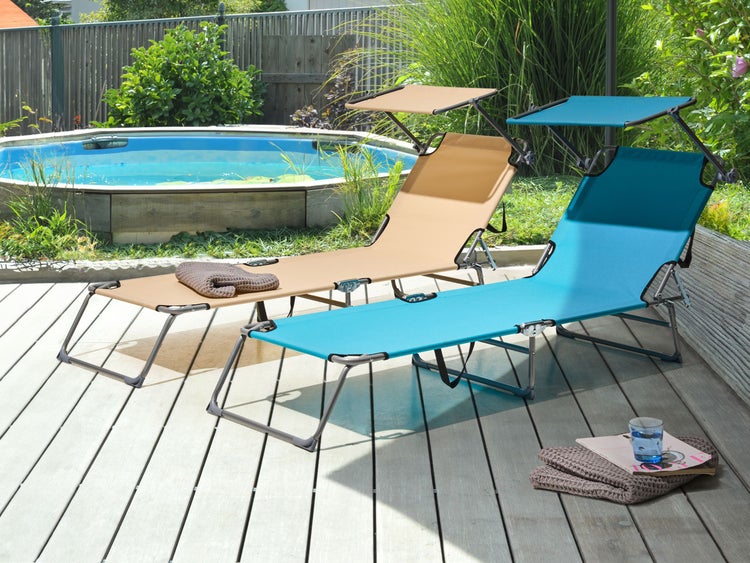 Zwei Sonnenliegen mit Sonnenschutz auf einer Holzterrasse neben einem Pool