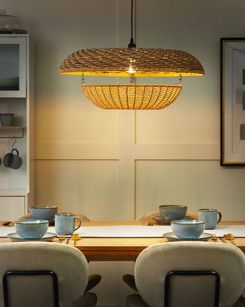 Szene mit einem Esstisch unter einer hängenden Korbgeflechtlampe.