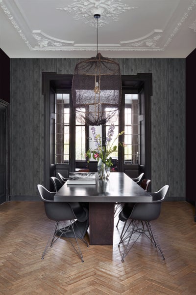 Esstisch mit Stühlen, Dekoration und Hängelampe in einem Esszimmer mit Paneelwand