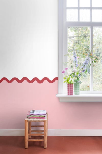 Dekoratives Interieur mit einer Wand in zwei Farben, einem Hocker mit Büchern und Blumen in Vasen auf einem Fensterbrett