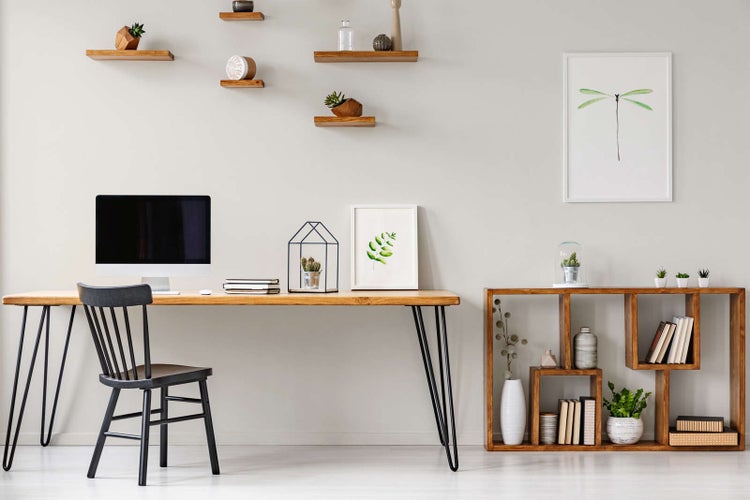 Heller, organisierter Arbeitsbereich mit einem Schreibtisch aus Holz mit Metallbeinen, einem Holzstuhl und einem niedrigen Regal aus Holz.