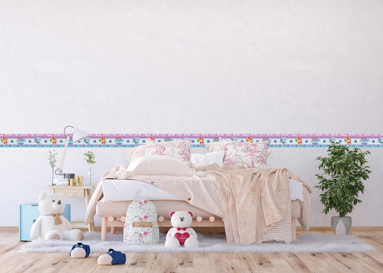 Helles Kinderzimmer mit Holzbett, gemusterter Bettwäsche und einer selbstklebenden Tapetenbordüre mit Paw Patrol Motiven an der Wand.