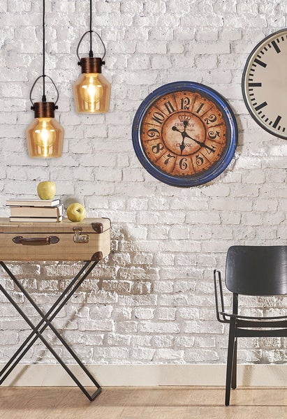 Dekorative Szene mit Pendelleuchten, Wanduhren, einem Koffer auf einem Ständer, Büchern, Äpfeln, einem Stuhl und einer Ziegelwand.