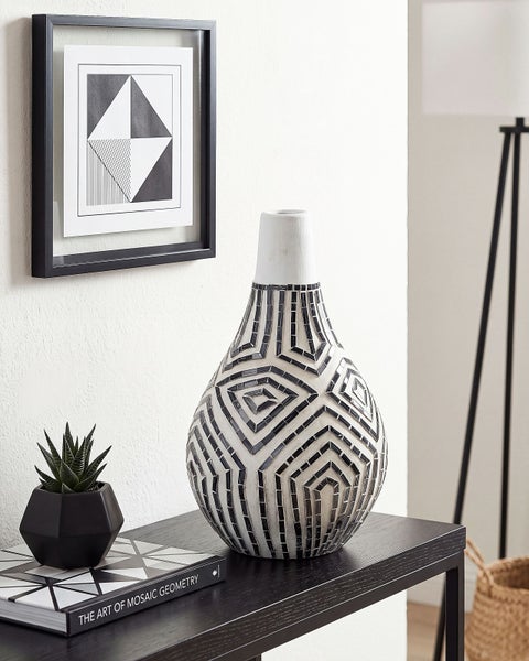Dekorative Vase mit Mosaikmuster aus kleinen Steinen auf einem schwarzen Konsolentisch neben einer Sukkulente und einem gerahmten Bild an der Wand.