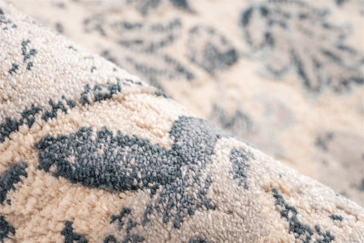 Nahaufnahme eines weichen Teppichs in Blau und Creme mit floralem Muster und dichtem Flor.