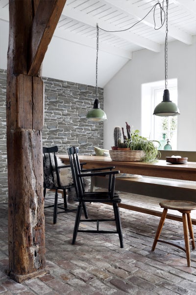 Esszimmer mit Holztisch, Stühlen, Steinwand und Pendelleuchten