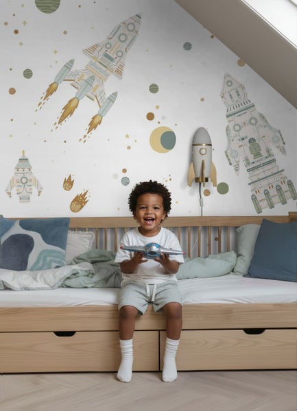 Kinderzimmer mit Weltraum-Tapete mit Raketen, Planeten und Sternen hinter einem hellen Holzbett.