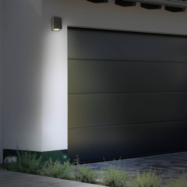 Quadratische Außenwandleuchte neben Garagentor an Hauswand