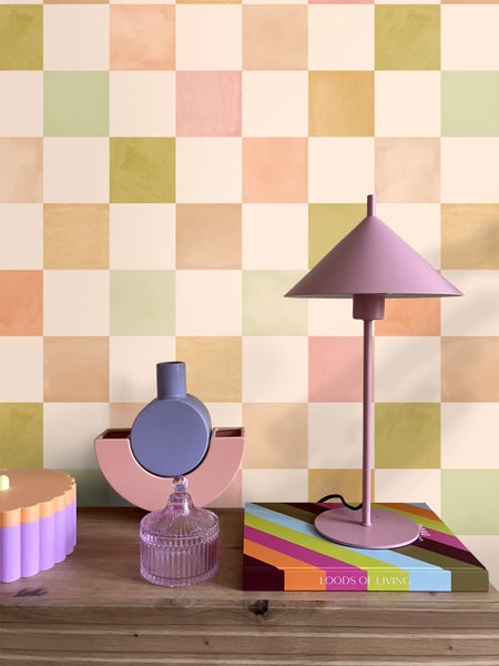 Dekorative Inneneinrichtung mit Tischlampe und Accessoires vor gemusterter Tapete.