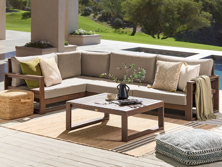 Gartenszene mit Ecksofa, Couchtisch, Teppich und Pouf auf einer Terrasse