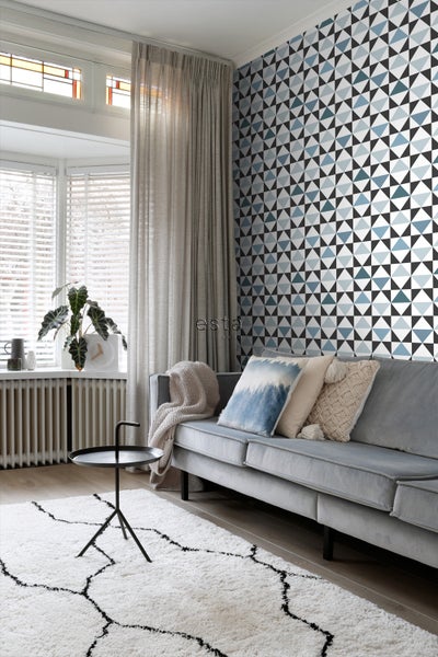 Wohnzimmer mit Sofa, Teppich und geometrischer Tapete