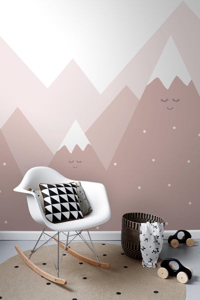 Dekoratives Kinderzimmer mit Schaukelstuhl, Kissen, Teppich und Wandgestaltung mit Bergmotiv