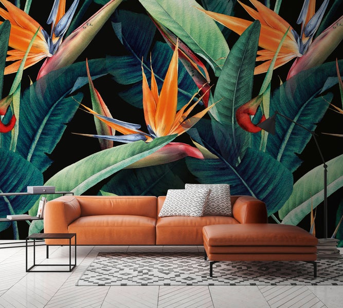 Fototapete mit tropischem Motiv aus Strelitzien und großen Blättern hinter einem Ledersofa in einem modern eingerichteten Wohnzimmer.