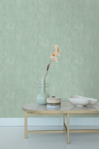 Dekoratives Interieur mit Vase, Schale und Dose auf einem Tisch vor einer Wand mit Tapete.