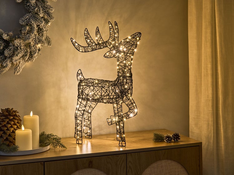 Dekorative Rentierfigur mit Beleuchtung als weihnachtliche Dekoration auf einem Sideboard.