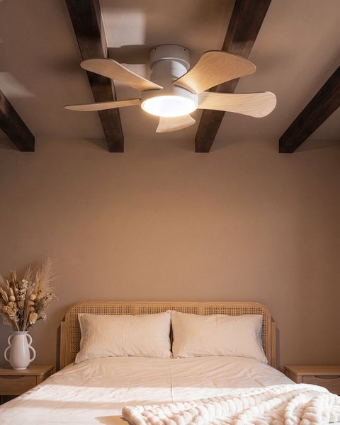 Ein Deckenventilator mit Beleuchtung und Holzflügeln ist in einem Schlafzimmer mit rustikalen Holzbalken an der Decke montiert.