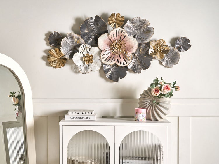 Dekorative Wandkunst mit Blumenmotiven über einem Sideboard mit Spiegel, Vase und dekorativen Büchern.