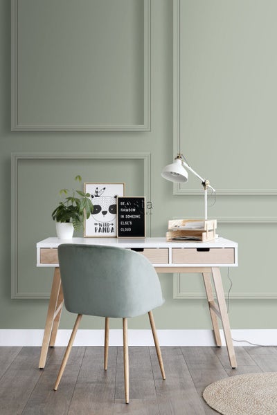 Arbeitszimmer mit Schreibtisch, Stuhl, Lampe, Pflanze und Wanddekorationen.