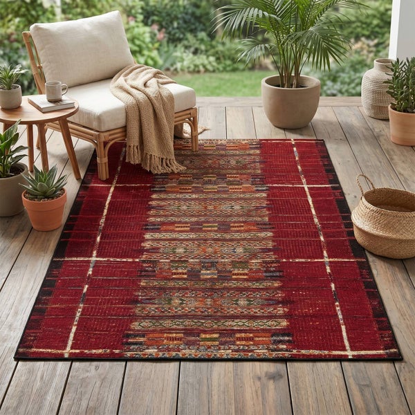 Roter Outdoor-Teppich mit Muster auf einer Holzterrasse mit einem Rattansessel, Beistelltisch und Topfpflanzen.