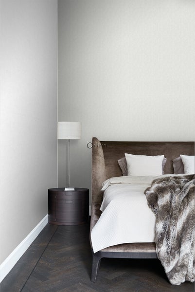 Schlafzimmer mit Bett, Nachttisch, Lampe und heller Tapete