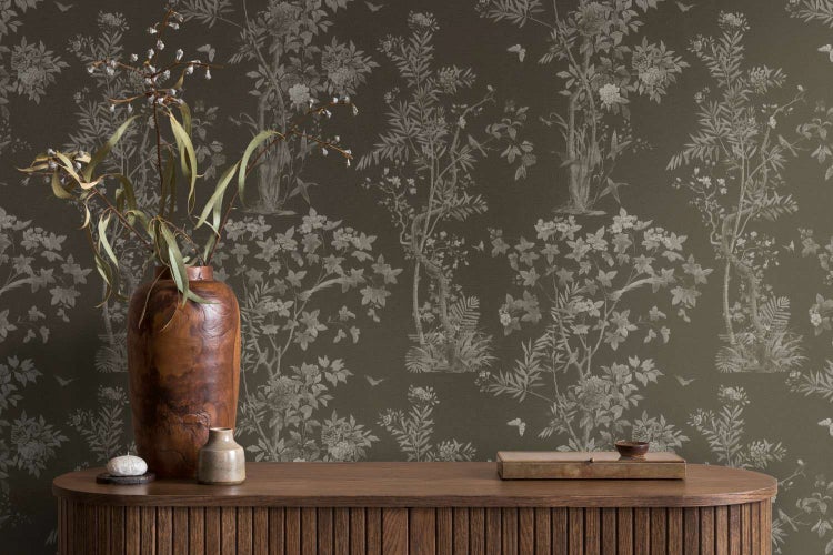 Vliestapete mit floralem Muster in Naturmotiv-Optik vor einer Holzkommode mit dekorativen Vasen in einem wohnlichen Ambiente