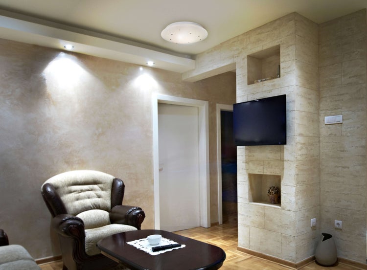 Wohnzimmer mit Sessel, Tisch und Wandgestaltung mit Fernseher