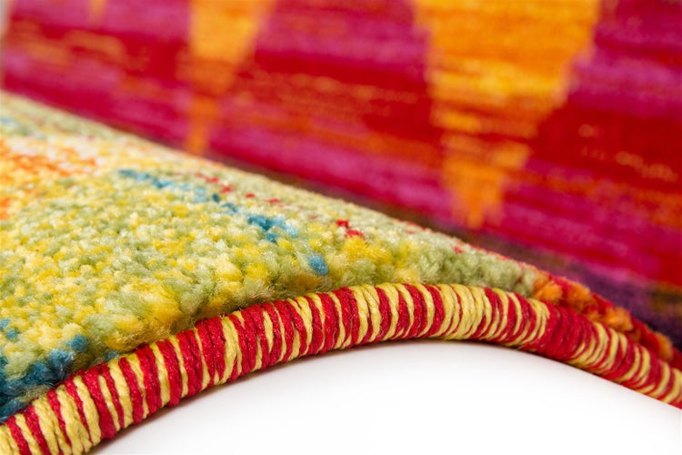 Nahaufnahme eines bunten Teppichs mit geketteltem Rand und weicher Textur.