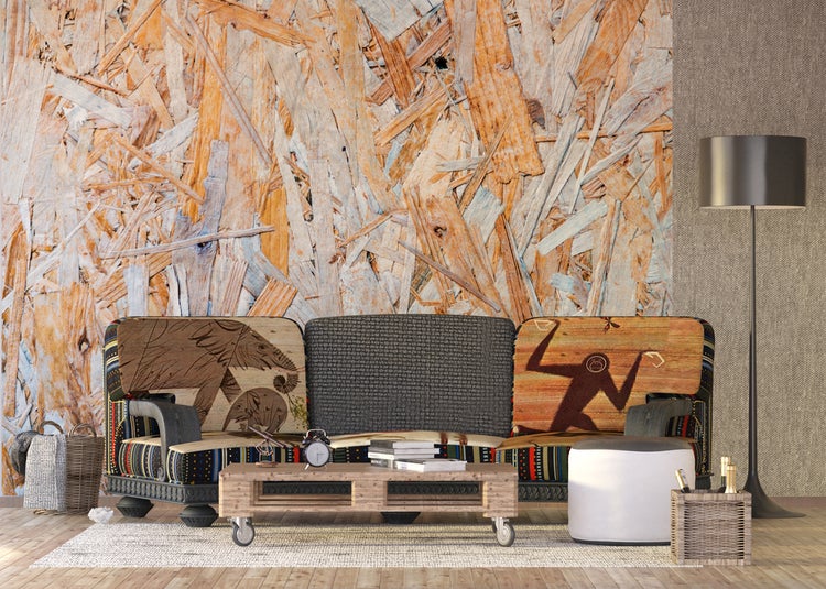 Wohnzimmer mit Sofa, Couchtisch aus Holzpalette und Stehlampe vor einer Wand aus Holzspanplatten.