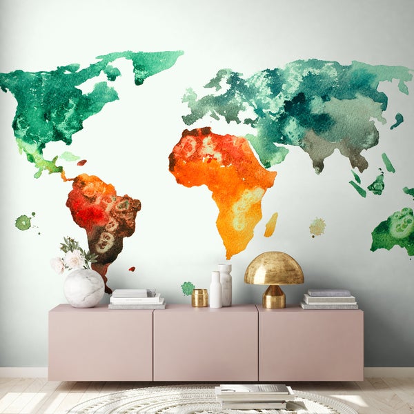 Fototapete mit einer Weltkarte in Aquarell-Optik an einer Wand in einem modern eingerichteten Zimmer mit Sideboard.